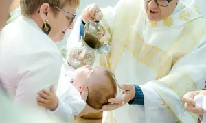 Chrzciny to wzruszająca uroczystość. Kapłan polewa wodą głowę dziecka, a rodzice trzymają je czule.