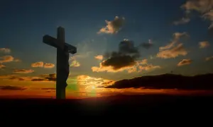 Krzyż z Jezusem na tle zachodzącego słońca. Czy modlitwa za osoby które popełniły samobójstwo jest skuteczna? Nadzieja w wierze.