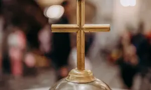 Złoty krzyż na ołtarzu, symbol wiary i 5 przykazań kościelnych. W tle rozmyte postacie wiernych.