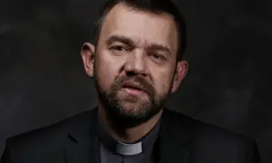 Duchowny z brodą w czarnym garniturze i białej kolarii. Jego spojrzenie sugeruje dylemat posłuszeństwa sumieniu a nauczanie hierarchów kościelnych.