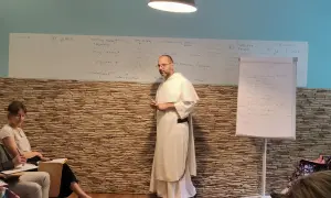 Wykład o tym, jak rozmawiać z niewierzącymi rodzicami o chęci powrotu do kościoła. Na tablicy schemat relacji i trudności.