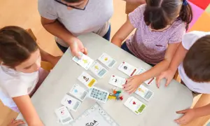 Gra karciana pomaga jak przygotować dziecko do pierwszej komunii świętej bez stresu. Dzieci i dorosły przy stole grają w grę edukacyjną.
