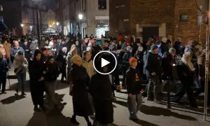 Tłum ludzi idzie ulicą nocą, trzymając świece. To uroczysta chwila, kiedy jest droga krzyżowa.