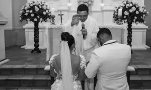 Ślub w kościele. Para młoda klęczy przed ołtarzem, ksiądz udziela błogosławieństwa. Zmiana parafii zamieszkania może wpłynąć na formalności kościelne.