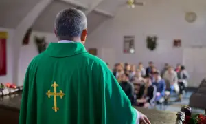 Ksiądz w zielonej szacie z krzyżem, przed wiernymi. Rozważania o skutkach ekskomuniki, czym jest i kogo może dotyczyć.