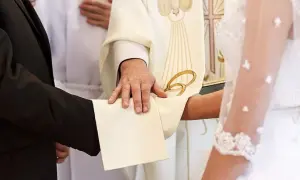 Odnowienie przysięgi małżeńskiej w kościele. Kapłan błogosławi parę, która trzyma się za ręce.