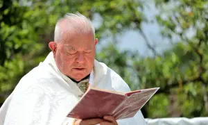 Duchowny w białej szacie czyta księgę. Zastanawia się, czy prezerwatywa to grzech, szukając odpowiedzi w świętych tekstach.