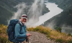 Uśmiechnięty turysta z plecakiem na szlaku. Czy warto jechać na pielgrzymkę do miejsc świętych? Propozycje tras i inspiracje.