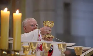 Kapłan podnosi kielich podczas mszy. Poradnik: jak zachować się na pierwszej mszy świętej dla gości.