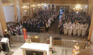 W kościele trwa litania do wszystkich świętych. Wierni i duchowni zgromadzeni na nabożeństwie, wśród nich osoby w strojach regionalnych.