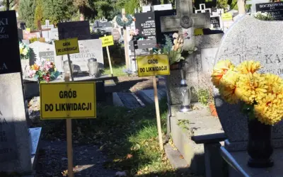 Żółte tabliczki "Grób do likwidacji" na cmentarzu. Oznaczają skutki nieopłacenia grobu po 20 latach i procedurę likwidacji.