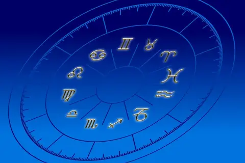 Złote symbole zodiaku na niebieskim tle. Praktykowanie magii i horoskopów może wpływać na życie duchowe katolika, odciągając od wiary.