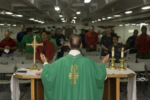 Kapłan prowadzi nabożeństwo, a wierni stoją z modlitwą. To obraz różnicy między religijnością a prawdziwą relacją z Bogiem.