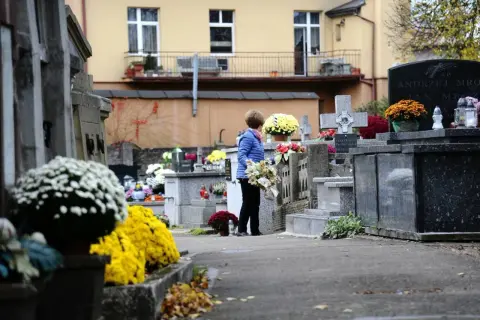 Kobieta z kwiatami na cmentarzu. Warto wiedzieć, jak odszukać groby żołnierskie i miejsca pamięci narodowej, by oddać im cześć.