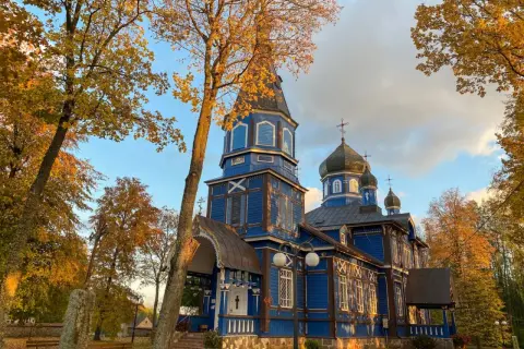 Niebieska cerkiew na Podlasiu, z kopułami i krzyżami, w jesiennym otoczeniu. Jak rozpoznać architekturę sakralną różnych wyznań na Podlasiu?