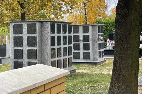Kolumbarium i kwatera urnowa: różnica między nimi, koszty i estetyka. Dwa szare, granitowe kolumbaria z czarnymi tabliczkami na urny.
