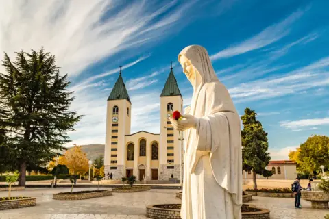 Pomnik Matki Bożej z różą przed kościołem. To miejsce objawień, nie tylko święte miasto.