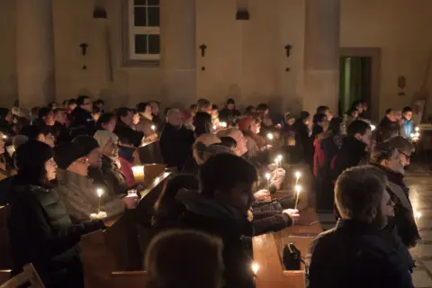 Ludzie z zapalonymi świecami w kościele podczas Rorat. Trwają one przez 24 dni Adwentu.