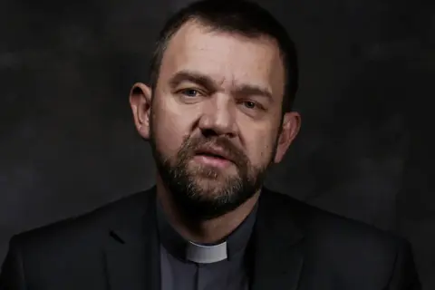 Duchowny z brodą w czarnym garniturze i białej kolarii. Jego spojrzenie sugeruje dylemat posłuszeństwa sumieniu a nauczanie hierarchów kościelnych.