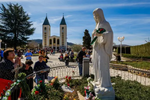 Pielgrzymi w Medziugorie modlą się przed figurą Matki Bożej. Przyczyny popularności Medziugorie mimo braku oficjalnego uznania dogmatu.