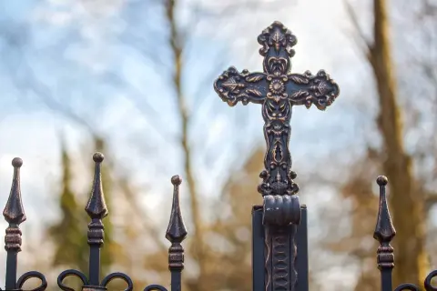 Krzyż na metalowym ogrodzeniu, symboliczne pytanie: jak pogodzić teorię ewolucji z opisem stworzenia świata w biblii?