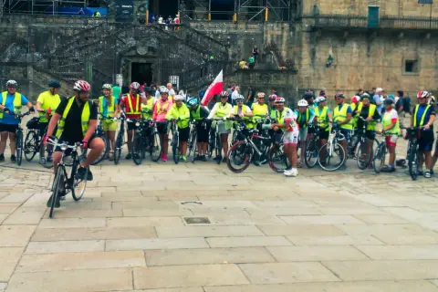 Grupa rowerzystów w kamizelkach odblaskowych przed katedrą. Szukasz najlepszych tras pielgrzymkowych w Polsce dla rowerzystów?