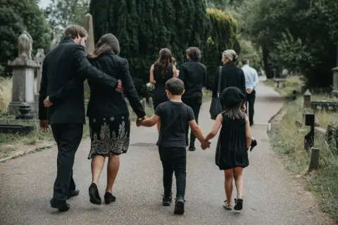Rodzina w żałobie idzie przez cmentarz. Pytanie, jak długo nie można ruszać rzeczy zmarłego, towarzyszy im w tej trudnej chwili.
