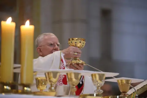 Kapłan podnosi kielich podczas mszy. Poradnik: jak zachować się na pierwszej mszy świętej dla gości.