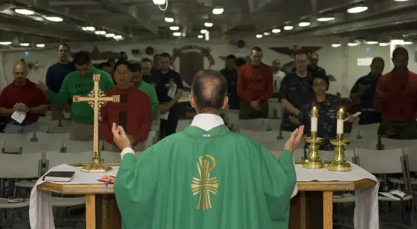 Kapłan prowadzi nabożeństwo, a wierni stoją z modlitwą. To obraz różnicy między religijnością a prawdziwą relacją z Bogiem.