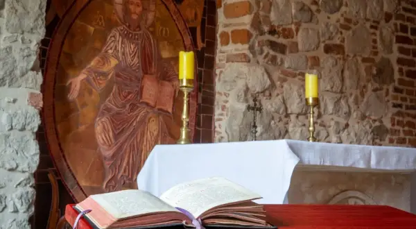 Ołtarz z otwartą księgą, świecami i mozaiką Chrystusa. Ilustruje etapy rozwoju wiary według psychologii rozwojowej.