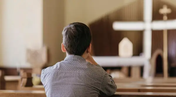 Chłopiec w kościele, zastanawiający się nad przyczynami odejść młodych ludzi z kościoła i dylematami pokoleniowymi.