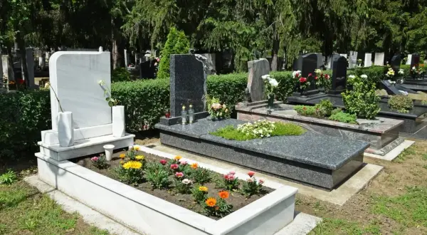 Zadbany grób z kwiatami i białym pomnikiem. Harmonogram prac, jak przygotować grób do Święta Zmarłych, obejmuje pielęgnację zieleni i porządkowanie.