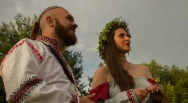 Para młoda w tradycyjnych strojach, symbolizująca żywą wiarę i tradycję przekazywaną w rodzinie.