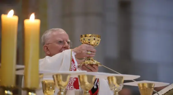 Kapłan podnosi kielich podczas mszy. Poradnik: jak zachować się na pierwszej mszy świętej dla gości.