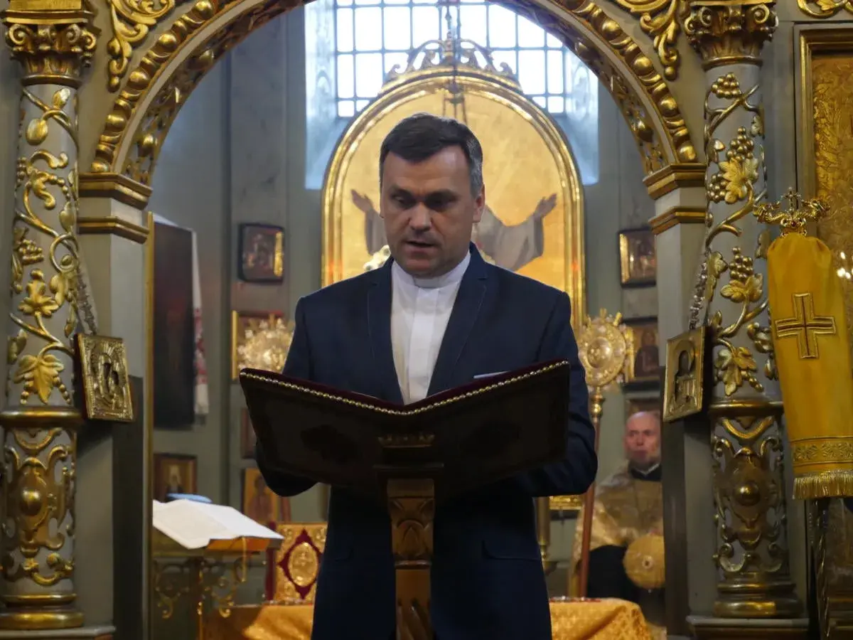 Duchowny w kościele polskokatolickim czyta z księgi. Wnętrze świątyni zdobią złote ornamenty i ikony.