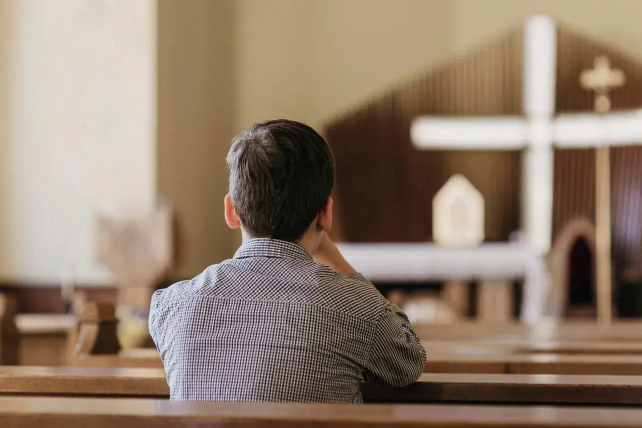 Chłopiec w kościele, zastanawiający się nad przyczynami odejść młodych ludzi z kościoła i dylematami pokoleniowymi.