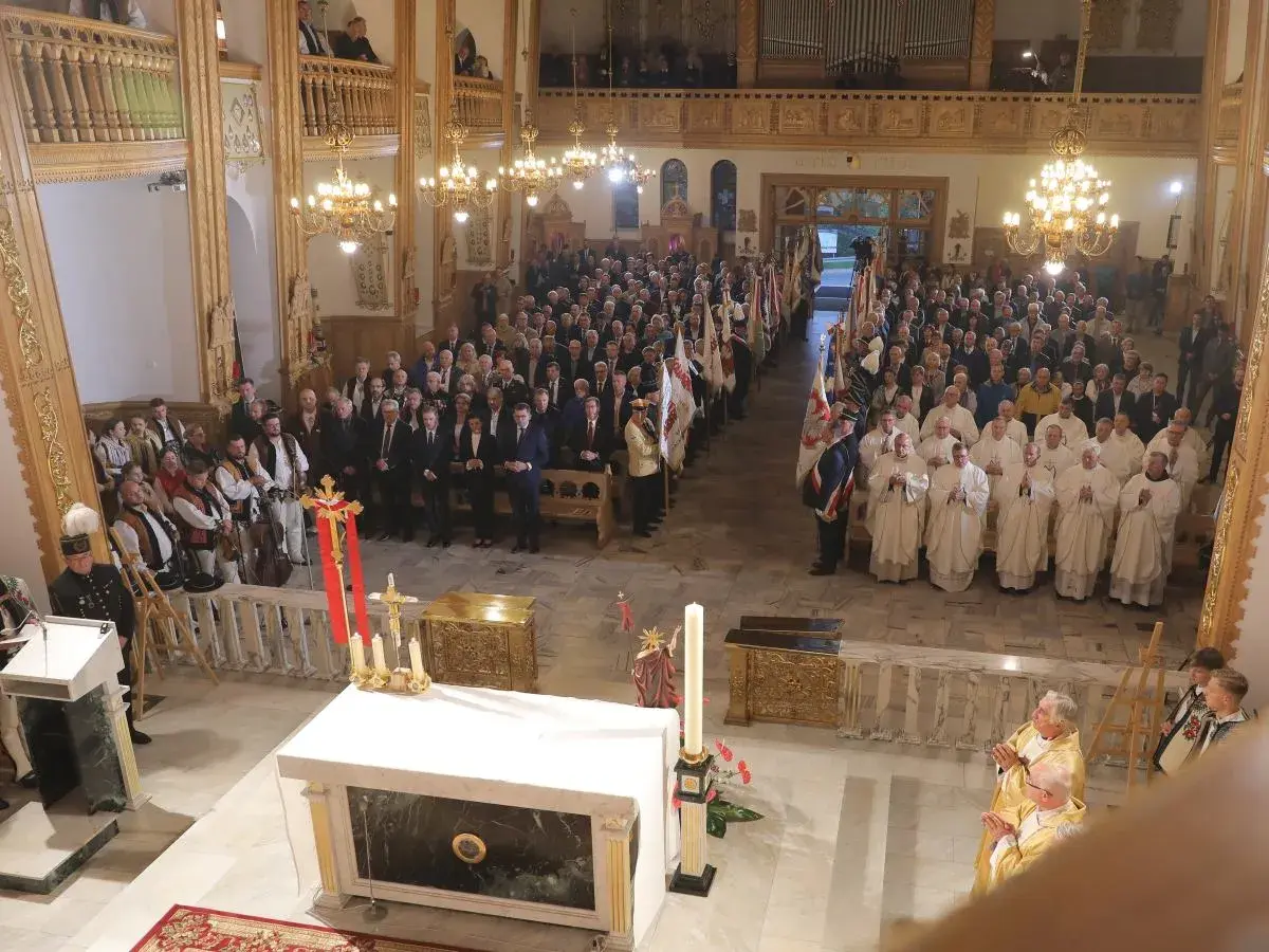 W kościele trwa litania do wszystkich świętych. Wierni i duchowni zgromadzeni na nabożeństwie, wśród nich osoby w strojach regionalnych.