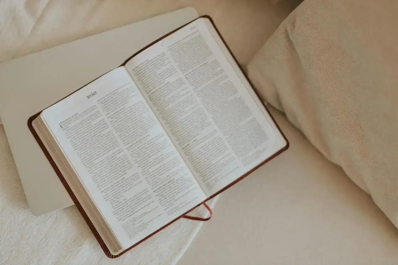 Otwarta Biblia na łóżku, symbol poszukiwań i jak znaleźć wspólnotę osób wierzących o podobnej wrażliwości.
