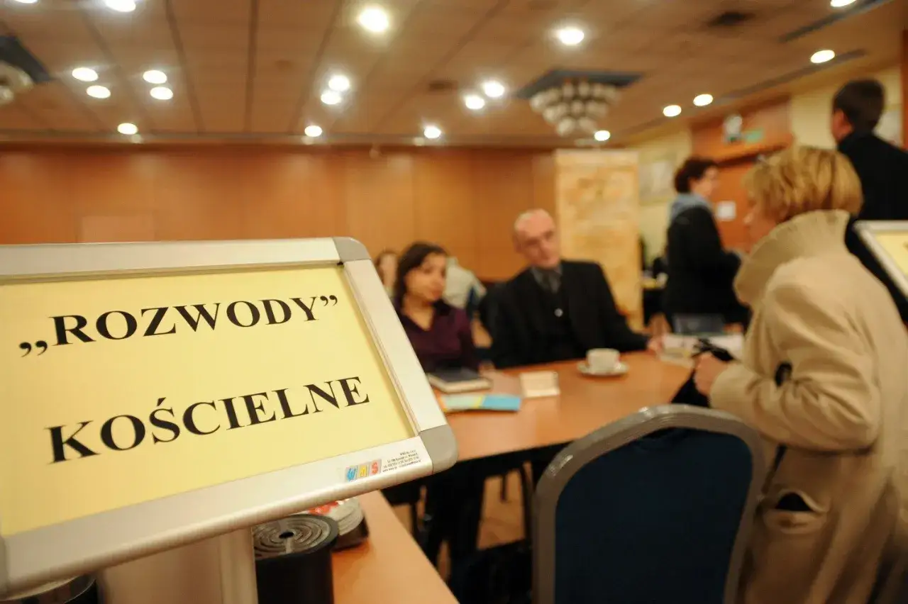 Dyskusja o przyczynach odrzucenia stwierdzenia nieważności małżeństwa kościelnego. Ludzie siedzą przy stole w sali konferencyjnej.