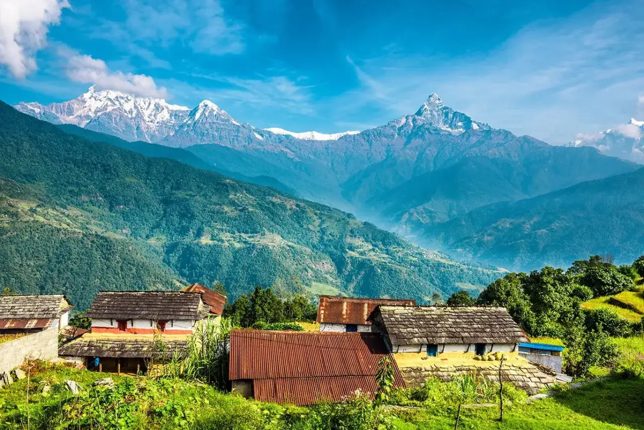 Widok na wioskę w Nepalu z ośnieżonymi szczytami w tle. Idealne miejsce, by odkryć, jakie miejsca święte w buddyzmie warto odwiedzić w Nepalu i Indiach.