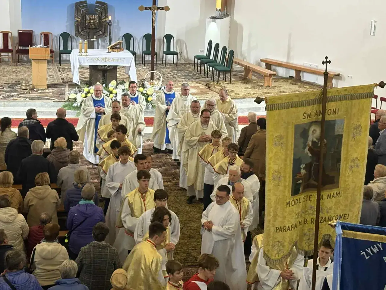 Procesja w kościele. Księża i wierni niosą sztandar z napisem 