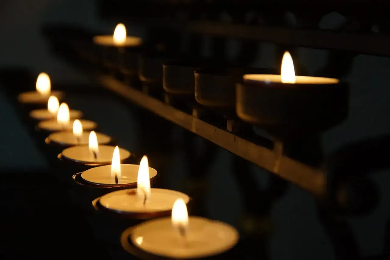 Płonące świece w kościele. Symbol nadziei i spokoju, gdy szukamy odpowiedzi, jak radzić sobie z gniewem na boga po ciężkiej chorobie.