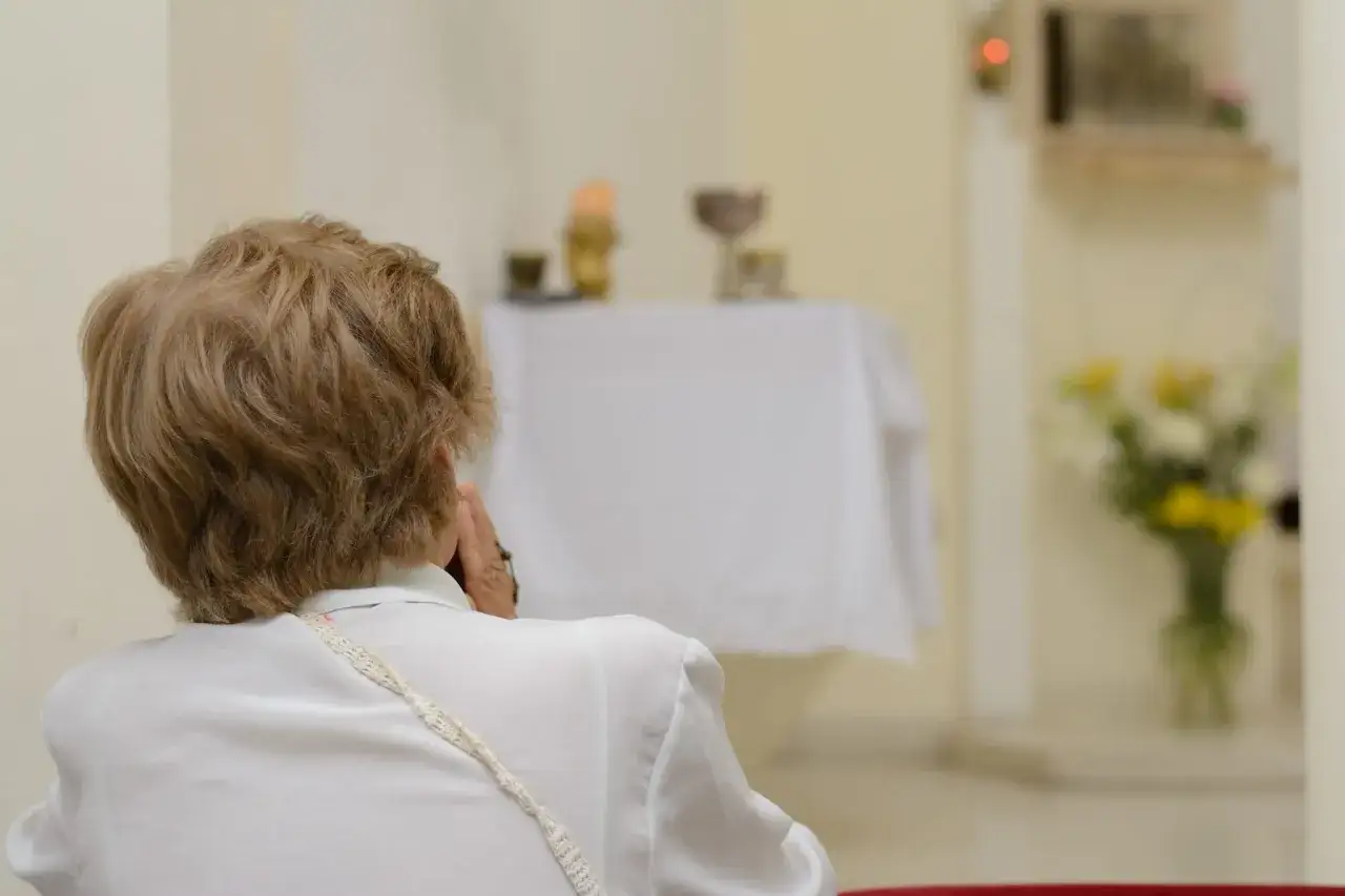 Kobieta modli się w kościele. Rozważamy skutki nieobecności na mszy niedzielnej w świetle prawa kanonicznego.