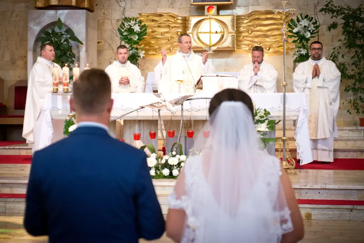 Ślub w kościele. Para młoda przed ołtarzem, ksiądz udziela błogosławieństwa. Zmiana parafii zamieszkania dla formalności kościelnych może być skomplikowana.