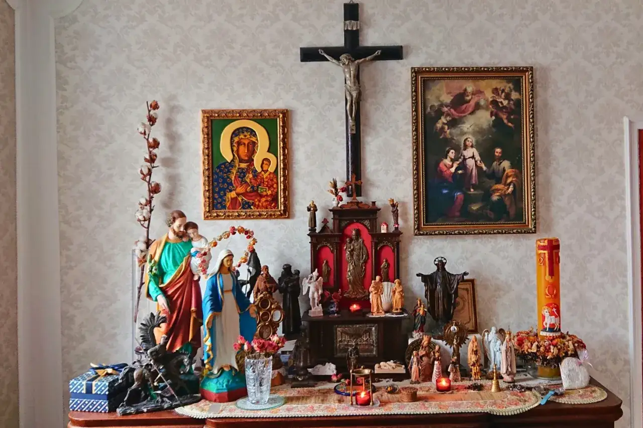 Ołtarzyk domowy do modlitwy rodzinnej: krzyż, obrazy świętych, figurki Maryi, Jezusa, aniołów i świece.