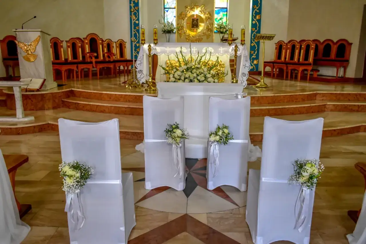Pięknie udekorowane krzesła w kościele, gotowe na jubileusz małżeństwa i odnowienie przysięgi.