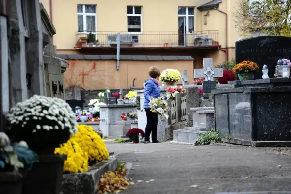 Kobieta z kwiatami na cmentarzu. Warto wiedzieć, jak odszukać groby żołnierskie i miejsca pamięci narodowej, by oddać im cześć.
