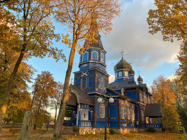 Niebieska cerkiew na Podlasiu, z kopułami i krzyżami, w jesiennym otoczeniu. Jak rozpoznać architekturę sakralną różnych wyznań na Podlasiu?