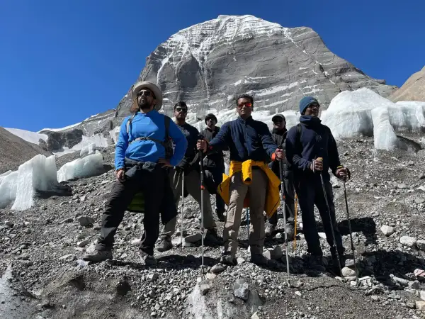 Grupa turystów z kijkami trekkingowymi na tle ośnieżonej góry. Przygotowanie do wędrówki na świętą górę Kailash w Tybecie wymaga odpowiedniego sprzętu.
