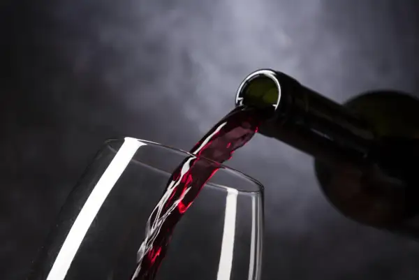 Czerwone wino leje się do kieliszka. Czy picie alkoholu w Adwencie to grzech?